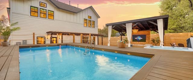 Modern white house with pool, hot tub, and covered patio at sunset